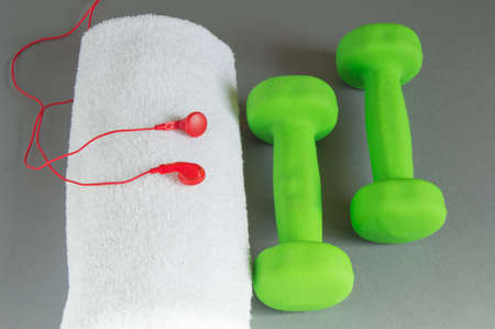 Fitness and diet concept background. Dumbbells green, red headphones and a white towel. The view from the topの写真素材