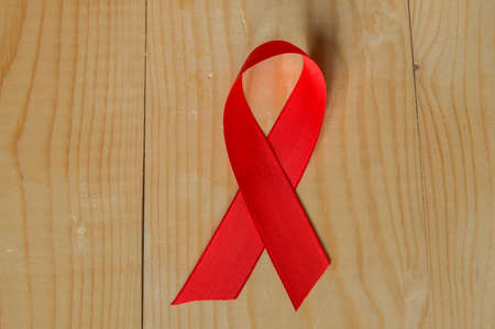 Awareness red ribbon on wood background: world day of fight against AIDS promotions to public support for the health of people living with HIV in Decemberの写真素材