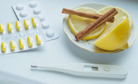 Thermometer, lemon, cinnamon and tablets - the treatment of colds.