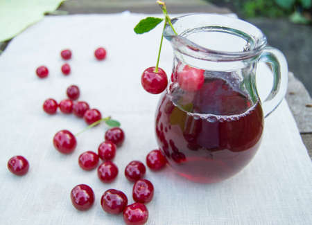 Cold cherry juice in jar and ripe berries, selective focus.の写真素材