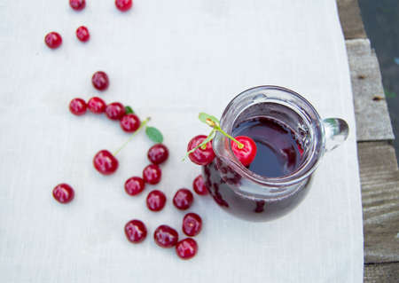 Cold cherry juice in jar and ripe berries, selective focus.の写真素材