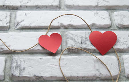 Two red hearts Valentines Day, white brick wall backgroundの写真素材
