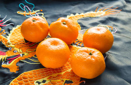 Chinese New year, mandarins in silk fabric with embroidered dragonの写真素材