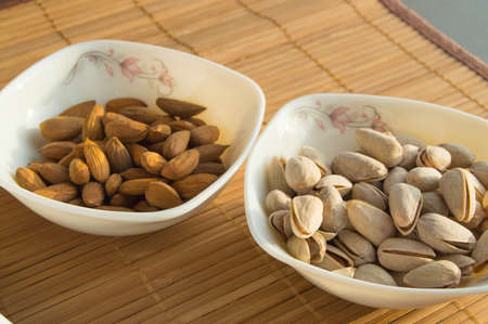 Two bowls of almonds and pistachios. Healthy meals snacks.の写真素材