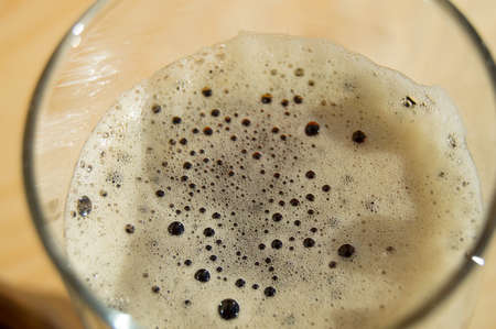 Glass of dark beer with foam on wooden background, top View