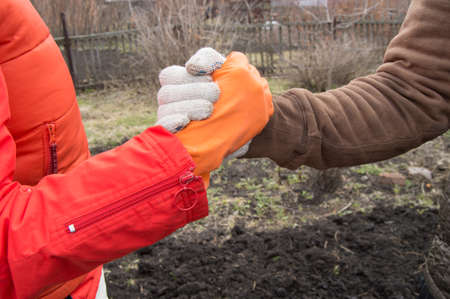handshake on the background of the soil men and women in work gloves.の写真素材
