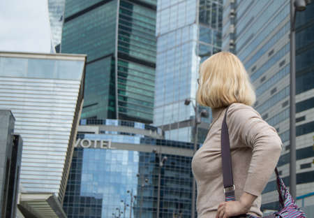 concept of travel, business travel, tourism - young woman with a shoulder bag in modern business center of cityの写真素材