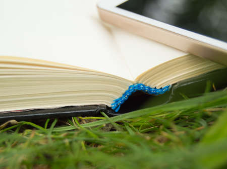 Books, smartphone on a green grass background, concept of education and trainingの写真素材