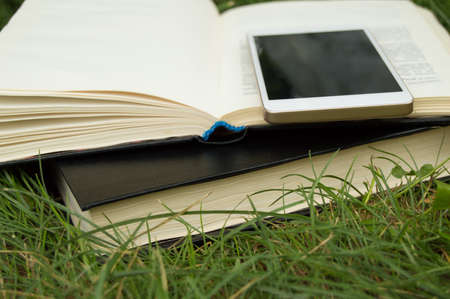 Books, smartphone on a green grass background, concept of education and trainingの写真素材