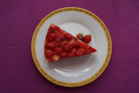 A piece of delicious strawberry cake with jello and strawberries lying on a beautiful plate, top...