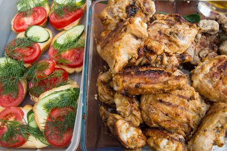 Tasty pieces of fried chicken on the grill and toast with tomatoes and cucumbers.の写真素材