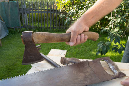 man holding the axe, working with construction tools in his garden