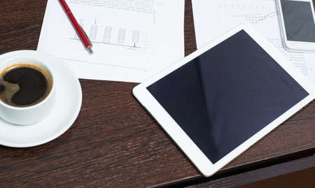 Workplace of businessman with digital tablet, smartphone, Cup of coffee and charts. The concept of a...