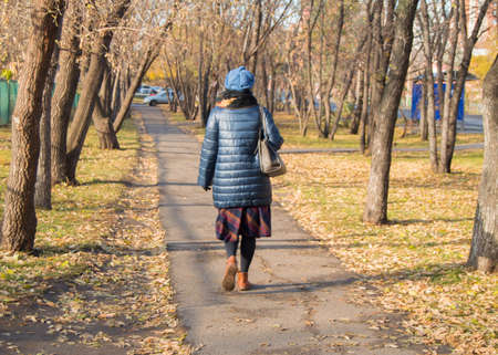 Fashionably dressed woman walking in the autumn Parkの写真素材