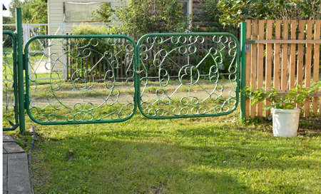 Green metal gate with a wicket - fence garden.の写真素材