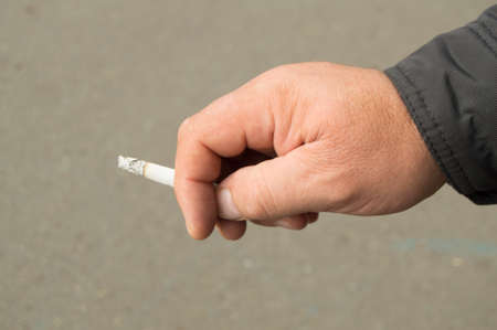 Cigarette in the hand of the old men, the concept of Smoking cessation, the fight against nicotine addiction.の写真素材
