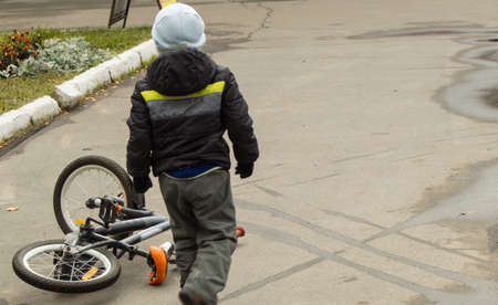 The boy fell off his bike and picks it up yourself.