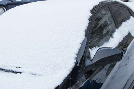 The parked car is on the road, covered with snowの写真素材