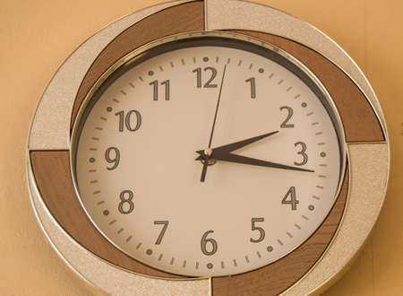 Round wall clock shows the time 2 hours and 15 minutes on light dial