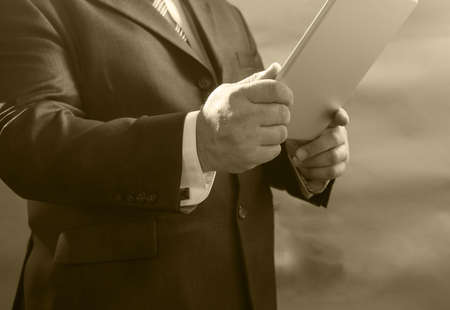 Close-up adult businessman standing in suit and use your tablet, gray.の写真素材