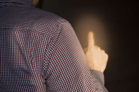 Index finger raised up, man shows gesture of attention, touch, point, back viewの写真素材