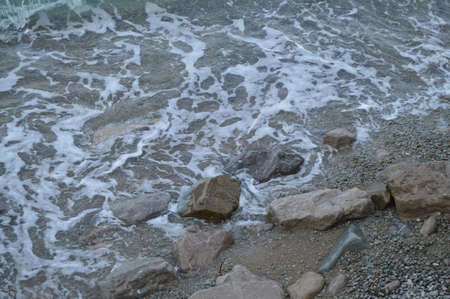 sea wave with foam beats on the rocks on the shore.の写真素材