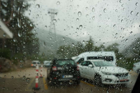 The road with the cars is photographed through the rain splattered windshield of the carの写真素材
