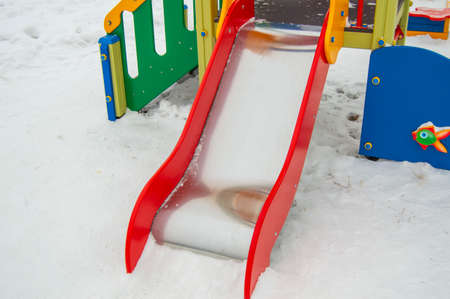 Empty metal slide for small children on snow-covered Playground, white snow background.の写真素材