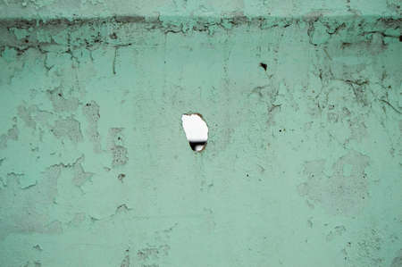 Hole shot in green wall with old peeling paint at target distanceの写真素材