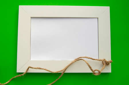 White blank frame with space for text lies on a green background, decorated with twine in knots,...