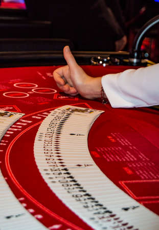 Italy - October 11, 2018, the dealer lays a playing card on the table with red cloth in a casino MSC Meraviglia.のeditorial素材
