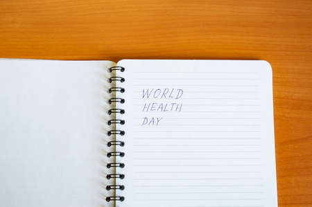 Notepad with text world health day on wooden table, health concept, minimalism style copy space.の写真素材