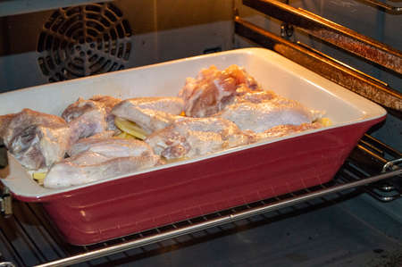Delicious homemade roast with chicken and potatoes, baked in a ceramic tray in a hot oven for a...