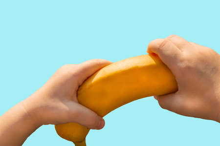 Ripe yellow banana in childrens hands, clipping on blue backgroundの写真素材
