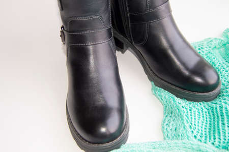 Fashionable and elegant womens winter leather shoes on white background, next green knitted jumper