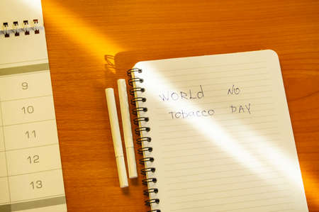 Flat lay, cigarettes and the inscription world no tobacco day written in a notebook, a healthy lifestyle without cigarettes.の写真素材
