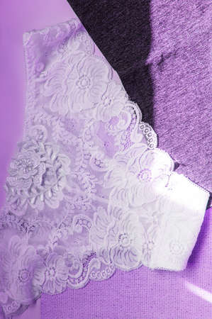 Lacy white sexy women's panties on purple neon background. Vertical shot, top view, flat lay.の写真素材