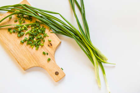 Fresh green onion feathers and cut into pieces on a wooden chopping Board. Top view, flat lay, copying space isolated on white background.の写真素材