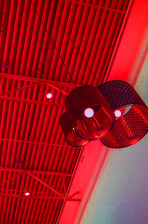 Ultra-modern loft style in red toned color decorative lamps and lampshades hang on long rope, industrial ceiling, interior design, vertical frame.の写真素材