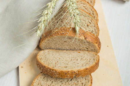 Fresh bread on a wooden chopping Board, wrapped in linen cloth, next to wheat ears, copy space, top...