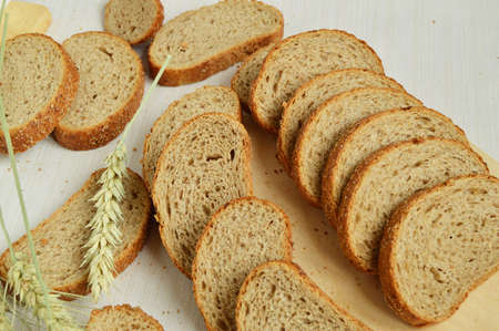 Fresh bread on a wooden chopping Board, wrapped in linen cloth, next to wheat ears, copy space, top...
