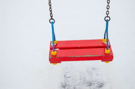 Empty childrens swing in the snow, swing on chains for the entertainment of children in winter