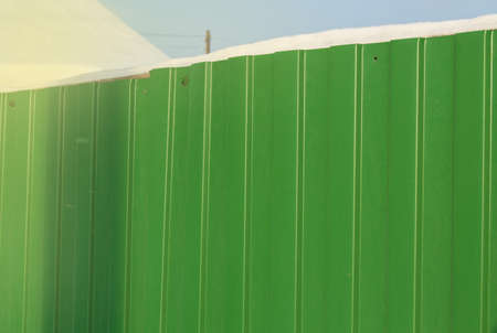 Modern green metal corrugated siding fence, outdoor winter space, safety and security, veneer texture.の写真素材