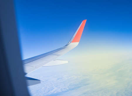 Looking through the plane window while flying on the wing with beautiful blue sky and Sunny dawn.