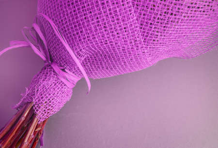 A bouquet of flowers is packaged in a lilac grid for flower arranging, close-up, outdoor frame.
