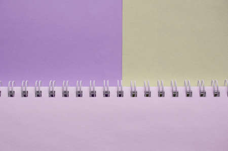 Open empty spiral notebook on a two-tone background of lilac and gray, top view, minimalism with a...