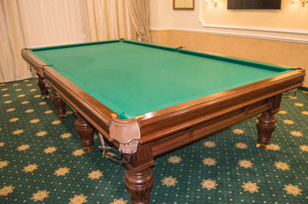 Billiard table with green baize stands in a luxurious living room, a concept of sports and Hobbies...