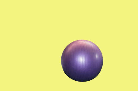 Large purple fitness ball isolated on yellow background by clipping.の写真素材