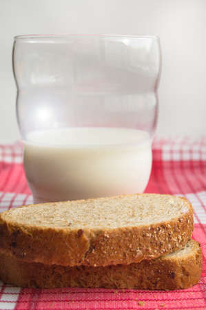 Vertical shot, a glass of milk with sliced pieces of coarse grain bread, the concept of a healthy...