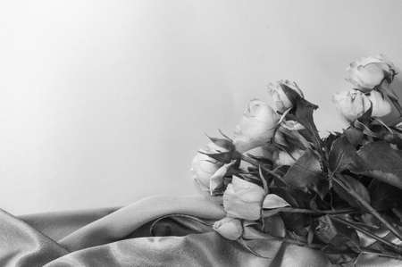 Black-and-white photo, a bouquet of roses on soft silk, flat bed, top view, ready-made layout, romance and love.の写真素材